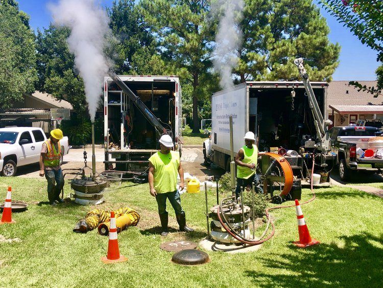 A Triplex crew setting a liner at a manhole on a residential street