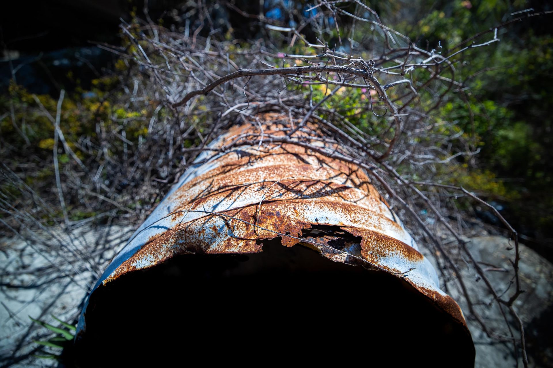 A corroded metal culvert with the invert gone, open to daylight