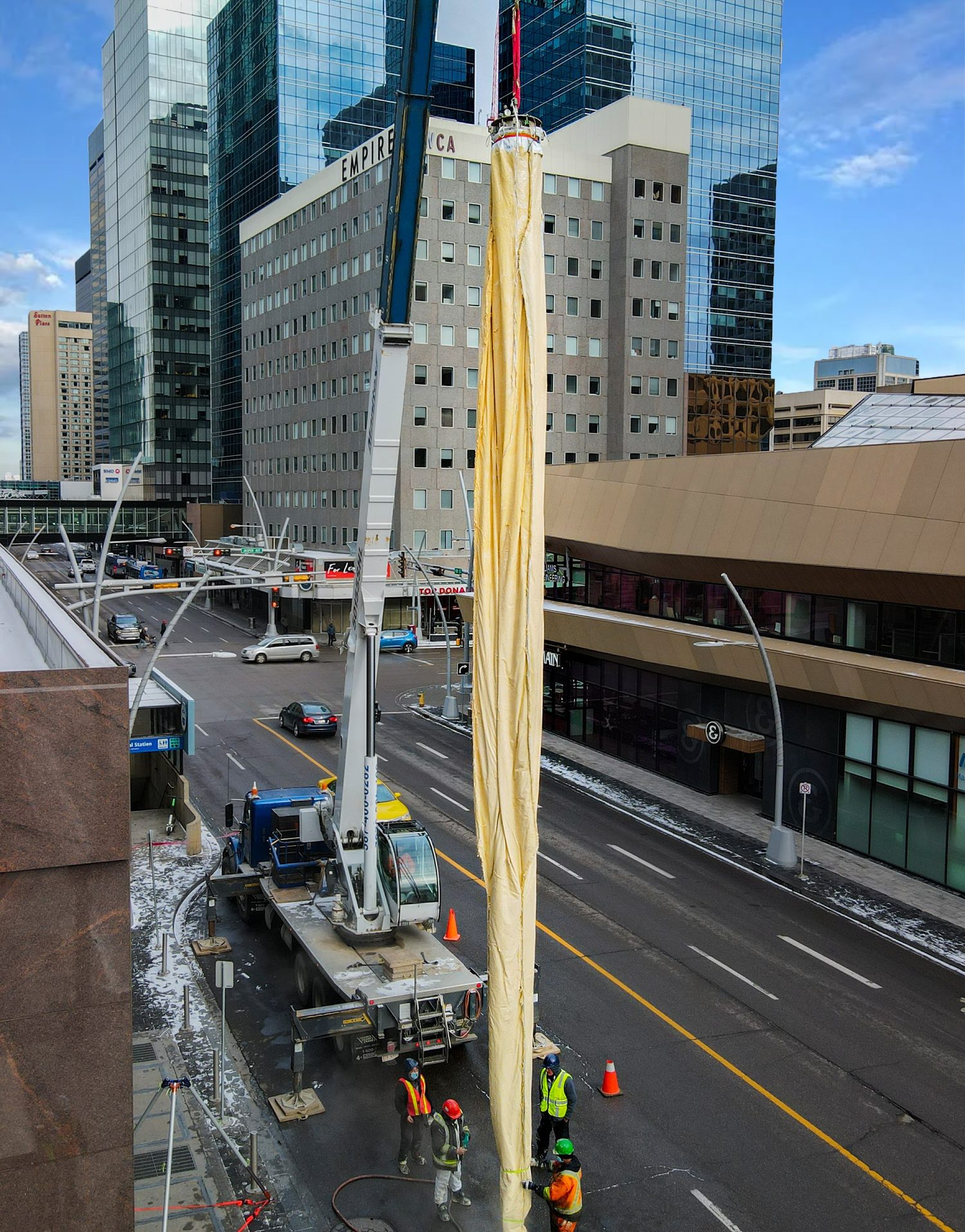 A Triplex Liner suspended from a crane between downtown buildings