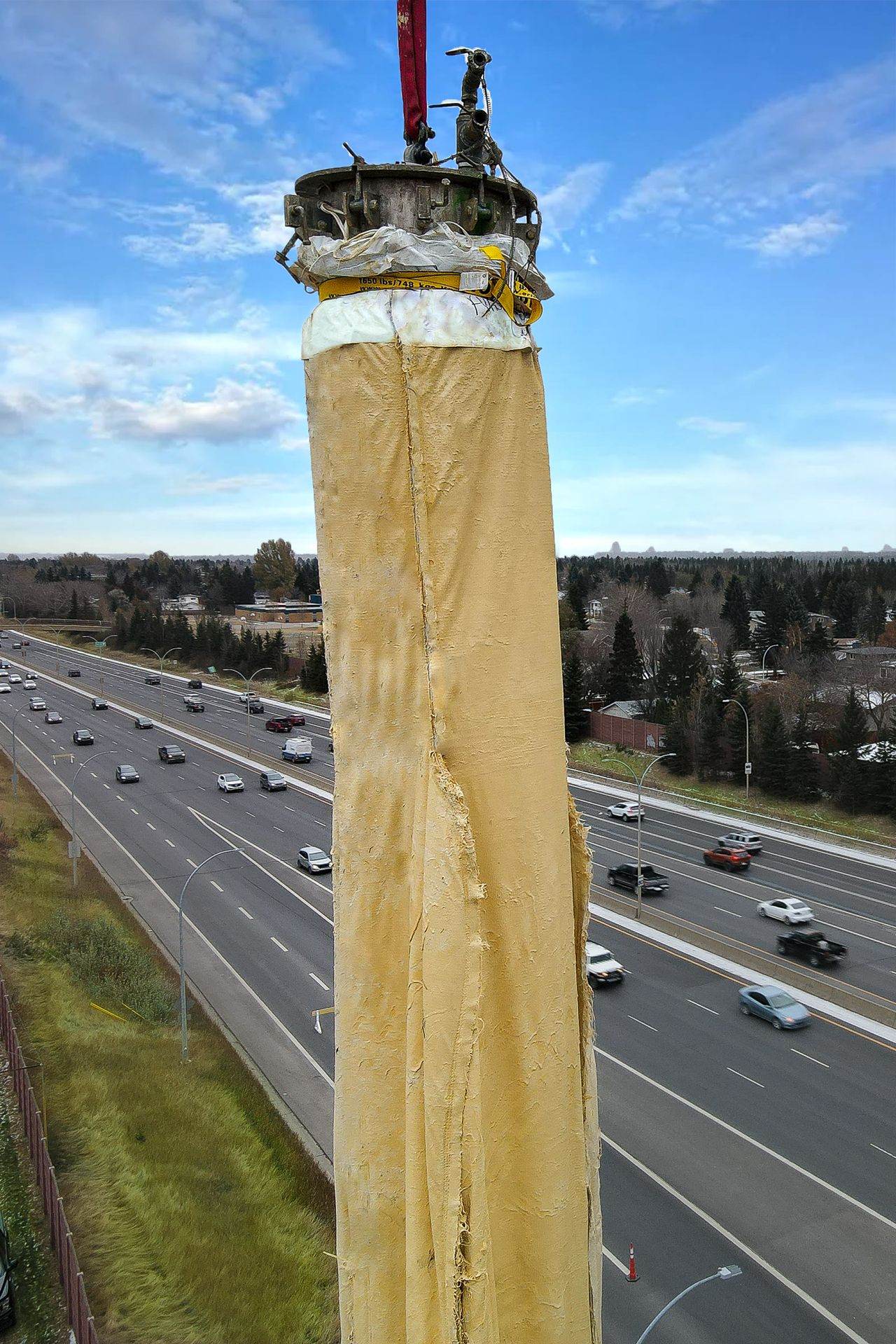 A Triplex Liner hanging vertically from a crane above a live highway