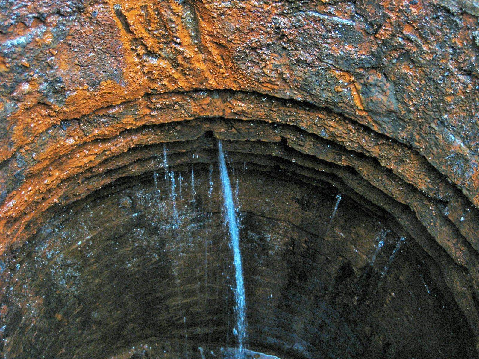 Groundwater infiltration running down the corroded wall of a sewer manhole